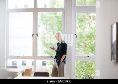 In der leeren Büro Geschäftsfrau am Smartphone suchen Stockfoto