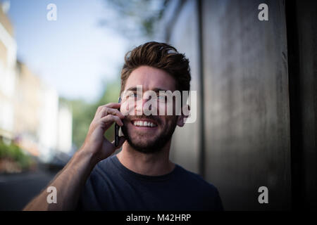 Junge Erwachsene zu Fuß die Straße runter am Telefon Stockfoto