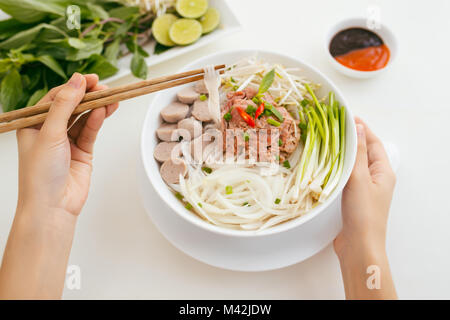 Frau essen traditionellen vietnamesischen Pho Nudeln mit Stäbchen. Stockfoto