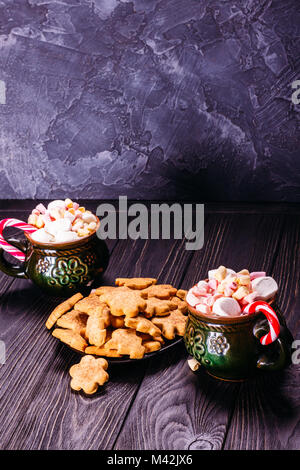 Becher mit Kaffee und Marshmallow mit Weihnachten Bonbons und Ingwer Kekse Konkrete dunklen Hintergrund mit Kopie Raum Stockfoto
