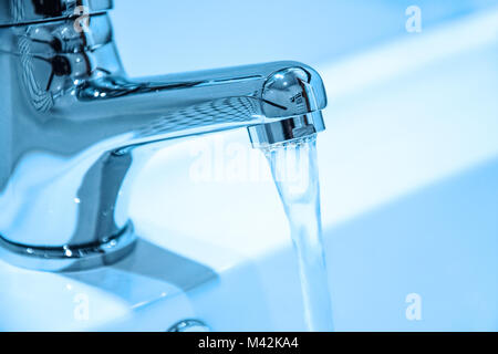 Wasser läuft aus dem Wasserhahn in close-up (blaue Filter Effekt). Stockfoto