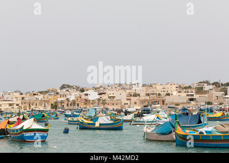 Ein Bild von einem Fischerdorf mit traditionellen Luzzu Boote im Vordergrund, Marsaxlokk, Malta Stockfoto