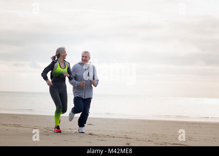 Älteres paar jogging am Strand Stockfoto