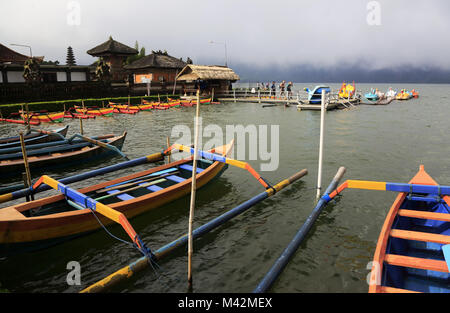 Jukungs die traditionellen Balinesischen Fischerbooten am Ufer des Lake Bratan mit Pura Ulun Danu Bratan Tempel im Hintergrund. Bali Indonesien Stockfoto