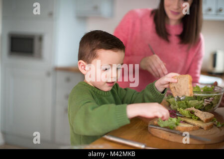 Junge, ein Sandwich mit Mutter helfen Stockfoto