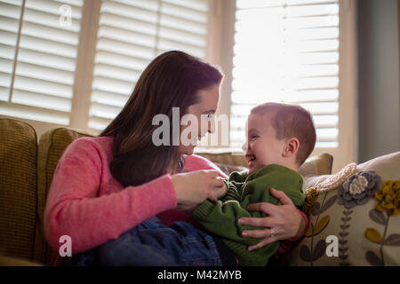 Mutter kitzeln Sohn auf dem Sofa Stockfoto