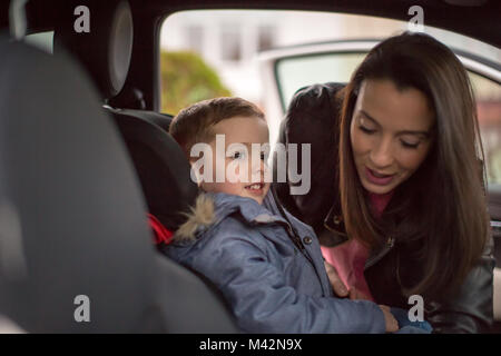 Mutter, Sohn in Autositz sicher Stockfoto