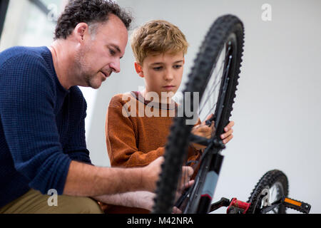 Junge Festsetzung Bike mit seinem Vati Stockfoto