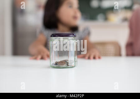 Mädchen speichern ihr Taschengeld in einem Glas Stockfoto