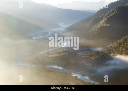 Punakha, Bhutan. Am frühen Morgen Sonne beleuchtet Morgennebel in der Mo River Valley. Stockfoto