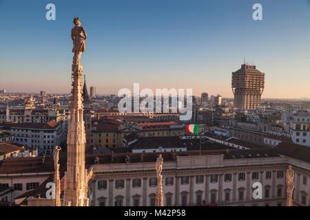 Mailand, Lombardei, Italien. Blick auf velasca Turm vom Dach des Doms Mailand bei Sonnenuntergang. Im Vordergrund steht die Statue Stockfoto