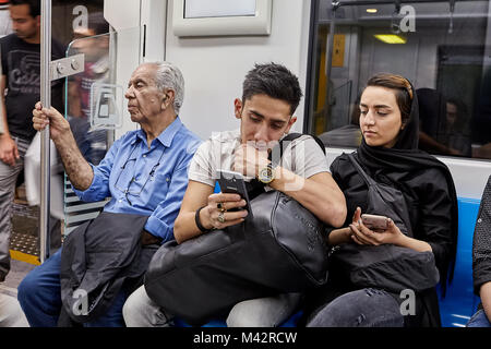 Teheran, Iran - April 28, 2017: Ein junger Iraner kommuniziert mit einem Mädchen in den Hijab im Fahrgastraum von der U-Bahn. Stockfoto