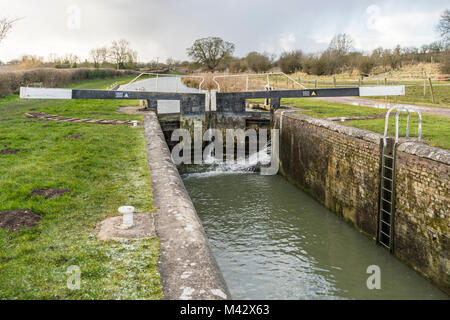 Wasser sprudelt durch eine Kanalschleuse mit Ausgleichsbalken am Kennet und Avon Kanal im Winter in Wiltshire, England, Großbritannien Stockfoto