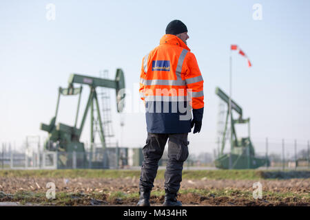 Emlichheim, Deutschland. 8 Feb, 2018. Geophysiker Tobias Fuhren steht vor einem Pferdekopf Pumpe in Emlichheim, Deutschland, 8. Februar 2018. Erdöl ist seit mehr als 70 Jahren in der Grafschaft extrahiert. Öl Produzent Wintershall zielt darauf ab, neue Ölfelder mit seismischen Messungen zu entdecken. Credit: Friso Gentsch/dpa/Alamy leben Nachrichten Stockfoto