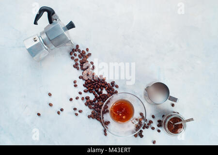 Gießen Kaffeebohnen von Moka Topf in ein Glas Espresso Tasse mit Untertasse. Kreative Ansicht von oben heißes Getränk Konzept mit kopieren. Kaffee brühen in Moka Stockfoto