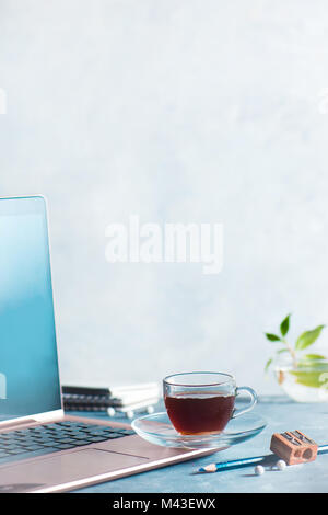 Laptop mit Espressotasse, Bleistifte öffnen und Notizen. Büro Arbeitsplatz kreatives Konzept auf einem weißen konkreten Hintergrund. Stockfoto