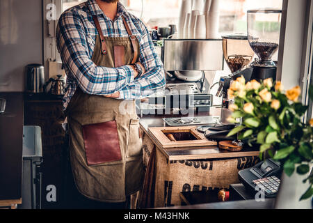Bärtige/Verkäufer auf seinem Arbeitsplatz in einem kleinen Straßencafe. Stockfoto