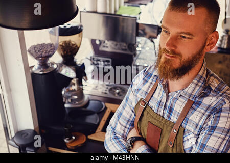 Bärtige/Verkäufer auf seinem Arbeitsplatz in einem kleinen Straßencafe. Stockfoto