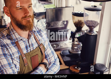 Bärtige/Verkäufer auf seinem Arbeitsplatz in einem kleinen Straßencafe. Stockfoto