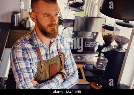 Bärtige/Verkäufer auf seinem Arbeitsplatz in einem kleinen Straßencafe. Stockfoto