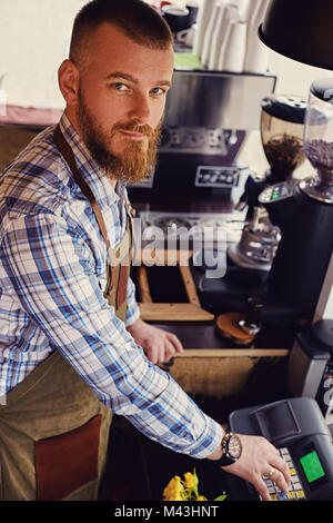 Bärtige/Verkäufer auf seinem Arbeitsplatz in einem kleinen Straßencafe. Stockfoto
