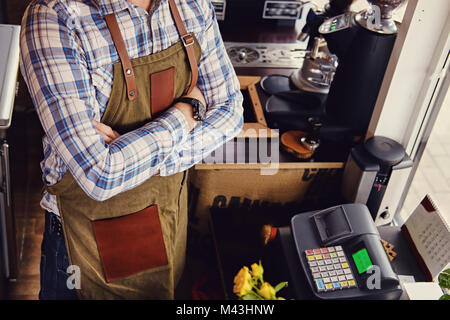 Bärtige/Verkäufer auf seinem Arbeitsplatz in einem kleinen Straßencafe. Stockfoto