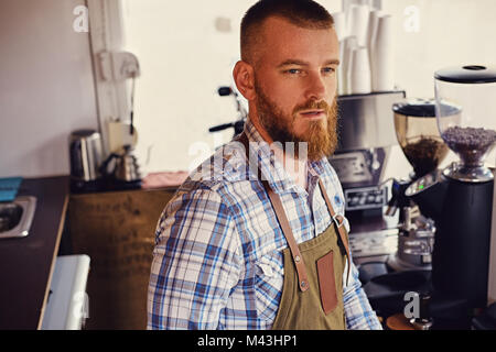 Bärtige/Verkäufer auf seinem Arbeitsplatz in einem kleinen Straßencafe. Stockfoto