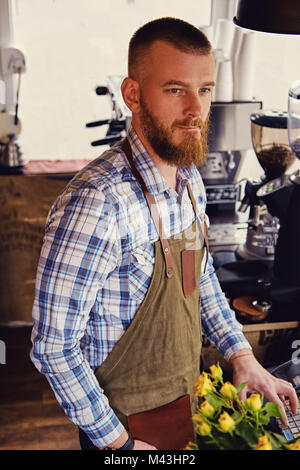 Bärtige/Verkäufer auf seinem Arbeitsplatz in einem kleinen Straßencafe. Stockfoto