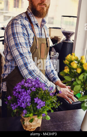 Bärtige/Verkäufer auf seinem Arbeitsplatz in einem kleinen Straßencafe. Stockfoto
