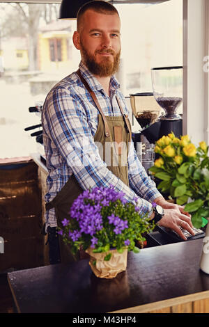 Bärtige/Verkäufer auf seinem Arbeitsplatz in einem kleinen Straßencafe. Stockfoto
