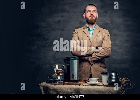 Ein Mann in der Nähe von einem Tisch mit Kaffee Maschine über grauen Hintergrund. Stockfoto