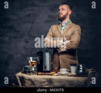 Ein Mann in der Nähe von einem Tisch mit Kaffee Maschine über grauen Hintergrund. Stockfoto