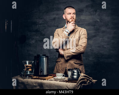 Ein Mann in der Nähe von einem Tisch mit Kaffee Maschine über grauen Hintergrund. Stockfoto