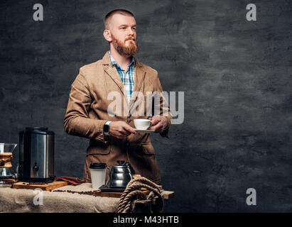 Ein Mann in der Nähe von einem Tisch mit Kaffee Maschine über grauen Hintergrund. Stockfoto