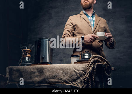 Ein Mann in der Nähe von einem Tisch mit Kaffee Maschine über grauen Hintergrund. Stockfoto