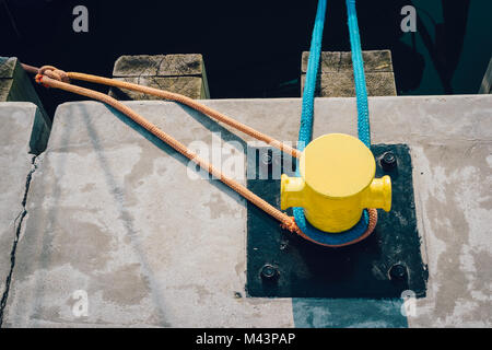 Gelbe Liegeplatz Poller am Pier mit Liegeplatz Seile Stockfoto