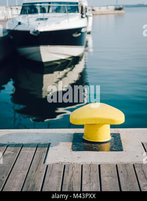 Liegeplatz Poller auf einem hölzernen Pier mit einer angedockten Luxusyacht im Hintergrund Stockfoto