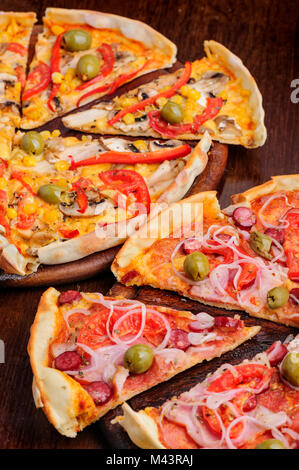 Pizza mit Salami, Peppeeoni, Oliven, Tomaten und gelbe Paprika Stockfoto