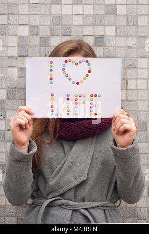 Junge Frau mit einem Papier mit den Worten "Ich leben Liebe' vor ihrem Gesicht Stockfoto
