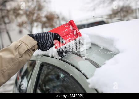 junge Frau tief Schneeräumen aus einem Auto mit einem Besen Stockfotografie  - Alamy