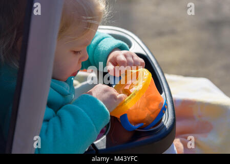 Nahaufnahme von einem kleinen Mädchen in Kinderwagen außerhalb im Herbst Holding snack Schale voller Goldfisch Stockfoto