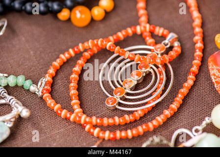 Serdolik (Karneol) Stein Kette Verlegung auf natürliche braune Bettwäsche Tischdecke. Yashma, orange Jaspis, Onyx Edelsteine herum. Heilung, kraftvolle Energie f Stockfoto