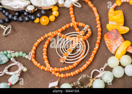 Serdolik (Karneol) Stein Kette Verlegung auf natürliche braune Bettwäsche Tischdecke. Yashma, orange Jaspis, Onyx Edelsteine herum. Heilung, kraftvolle Energie f Stockfoto