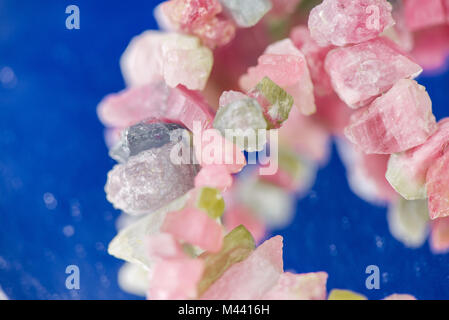 Makroaufnahme der Wassermelone turmalin Kristalle in Halskette. Natürliche, raue, ungeschliffene Steine. Schöne, Rosa und Grün Edelsteine auf blauem Hintergrund Stockfoto