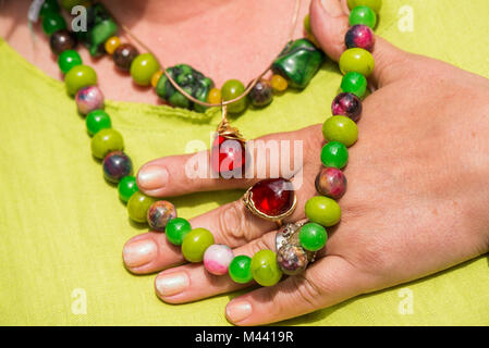 Frau mit schönen Edelstein Halskette und goldenen Ring mit Bernstein. Schmuck aus Korallen, Olivin und Achat Steinen. Kraftvolle Energie der Heilung Kristalle Stockfoto