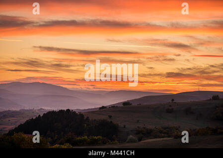 Romantisch, hellen und farbenfrohen Sonnenuntergang über eine Bergkette in Siebenbürgen. Schöne, bunte Herbst Hintergrund. Stockfoto