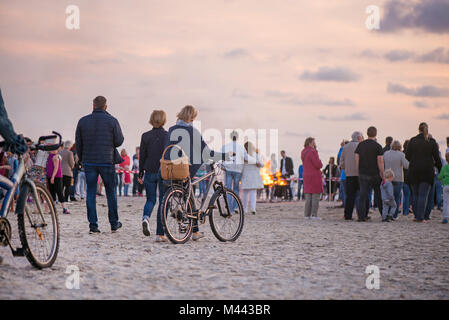 Romantische Lagerfeuer Nacht am Meer bei Sonnenuntergang. Leute versammeln um Nacht der alten Leuchten feiern. Große brennende Lagerfeuer Stockfoto