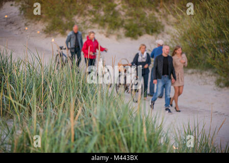 Romantische Lagerfeuer Nacht am Meer bei Sonnenuntergang. Leute versammeln um Nacht der alten Leuchten feiern. Wandern auf Holz weg am Meer Stockfoto