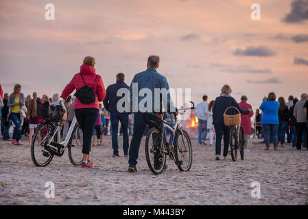 Romantische Lagerfeuer Nacht am Meer bei Sonnenuntergang. Leute versammeln um Nacht der alten Leuchten feiern. Große brennende Lagerfeuer Stockfoto