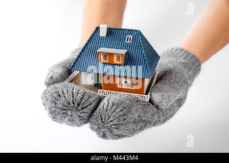 Haus Versicherung und Isolierung Konzept. Die Hände mit Handschuhen holding Miniatur Haus Modell Stockfoto